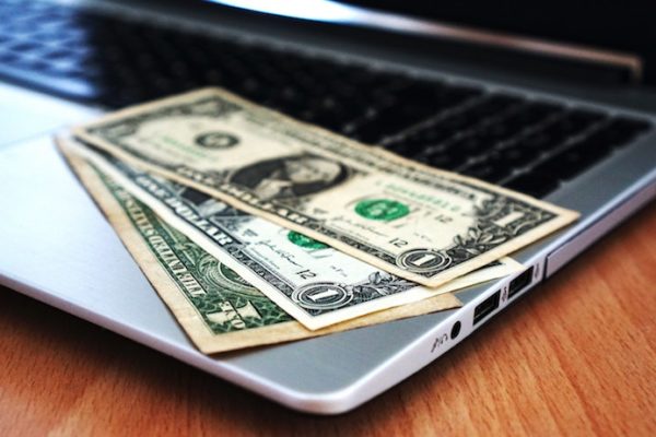 one dollar bills laying on a laptop computers