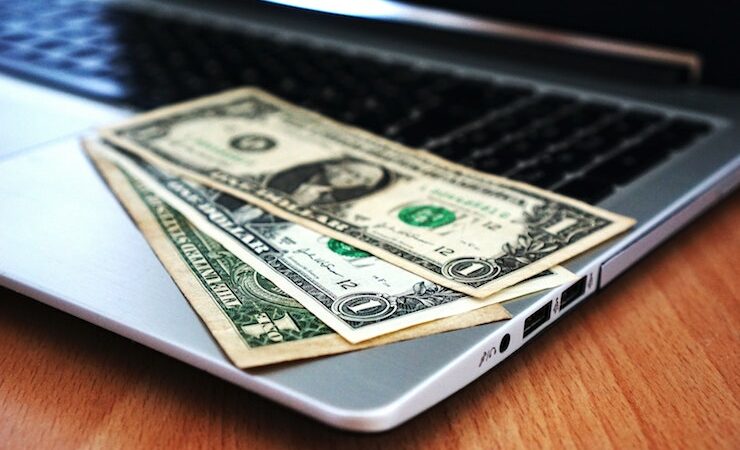 one dollar bills laying on a laptop computers