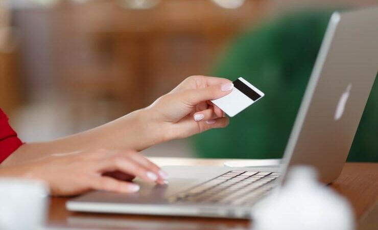 Woman holding credit card typing on laptop computer FI