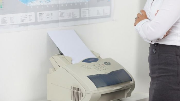 Woman standing by fax machine