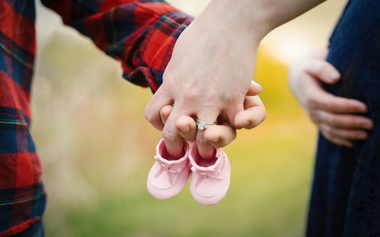 Couple holding hands and pink baby shoes
