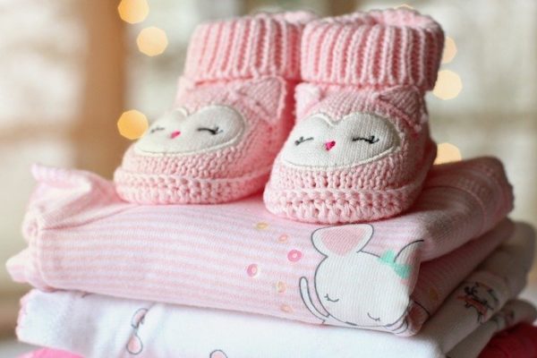 Pink booties sitting on top childrens clothes for babys