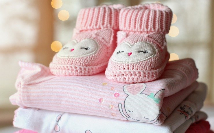 Pink booties sitting on top childrens clothes for babys