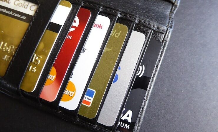 6 different credit cards in a black leather wallet laying on grey table