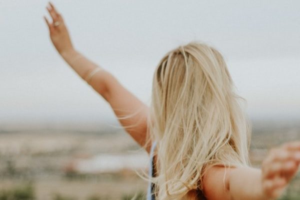 Blonde woman with her arms out in the air feeling free