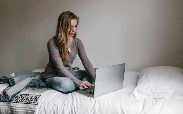 Mulher usando seu laptop acer na cama ao lado de sua jaqueta jeans