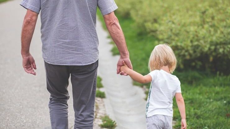 Man and little girl walking while holding hands