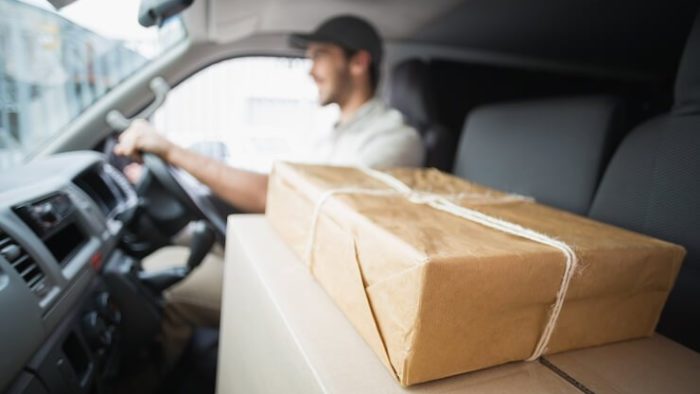 Man driving a car with packages in the passenger seat to be delivered