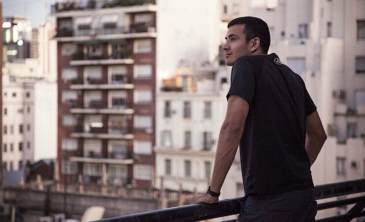 Man looking out to a city buildings full of apartments