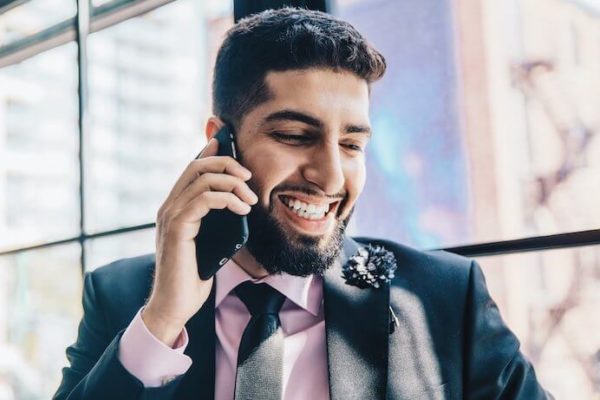 Man wearing suit using his cell phone while smiling