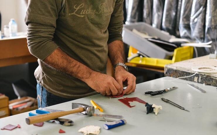 Hombre de camisa de manga larga verde trabajando en una artesanía en el taller de su casa