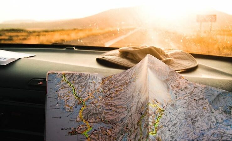 Real map sitting on dash of car driving down the road towards a sunset