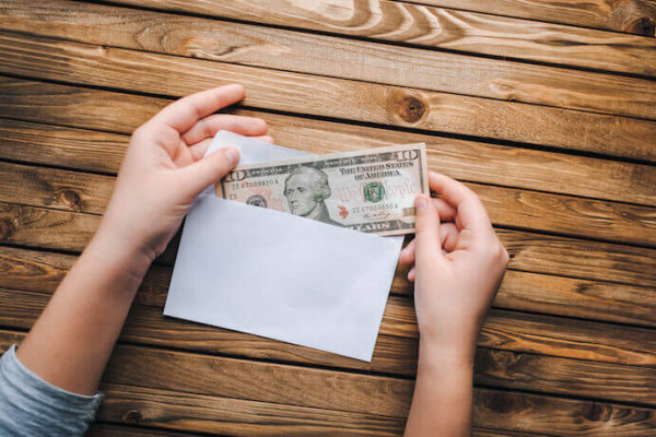 Woman putting 10 dollar bin into an envelope budgeting