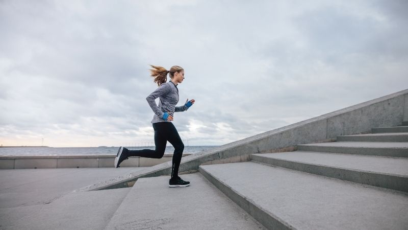 image of woman going for a jog outside next to water