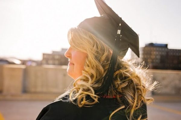 Graduate looking to the horizon while smiling with big blonde curls
