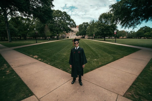 Student standing on campus happy that he graduated