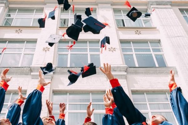 Students throwing their graduation caps in front of their school
