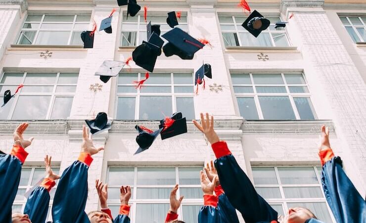 Students throwing their graduation caps in front of their school