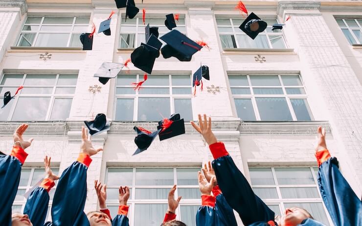 Students throwing their graduation caps in front of their school