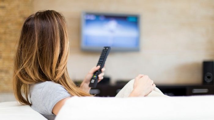 Woman watching tv while holding remote to change the channel