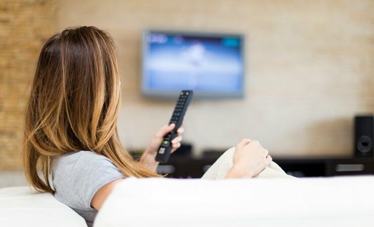 Woman watching tv while holding remote to change the channel