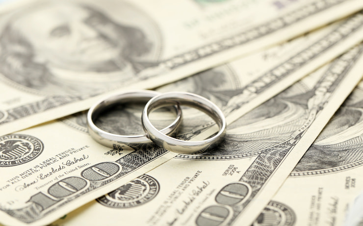 Wedding rings sitting on 100 dollar bills