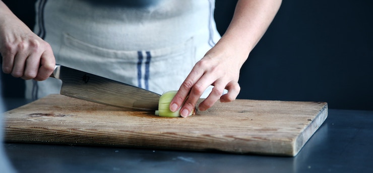 Donna che taglia una cipolla ad una lezione di cucina