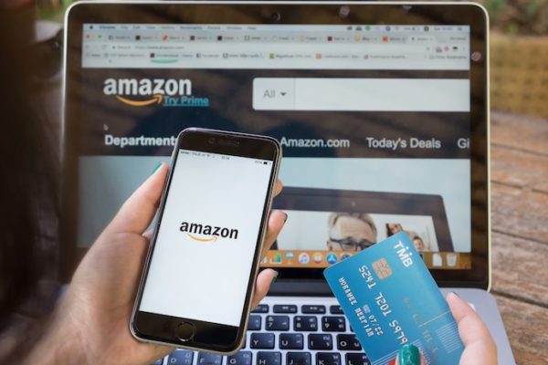 Woman looking at amazon on her phone and laptop while holding her credit card