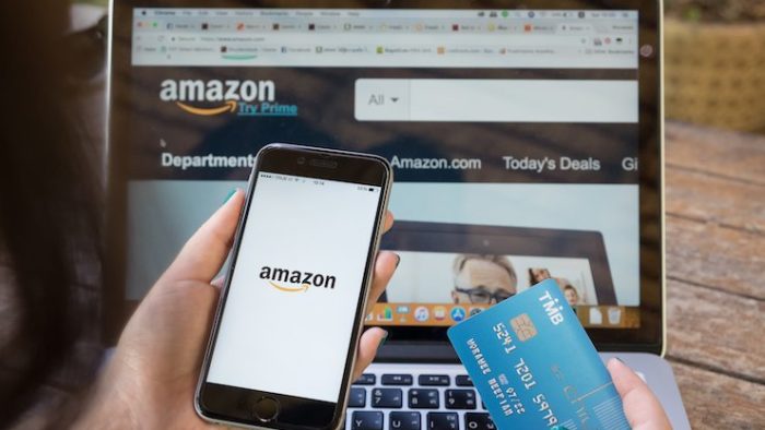 Woman looking at amazon on her phone and laptop while holding her credit card