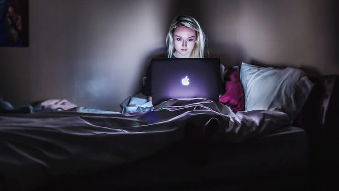 Woman researching health sharing plans in her bed