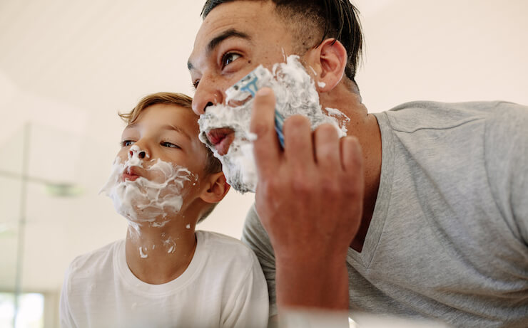 Father and son having fun with shaving cream and shaving their face