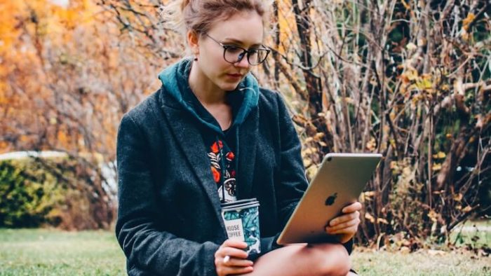 girl researching aspiration bank on ipad outside while drinking coffee