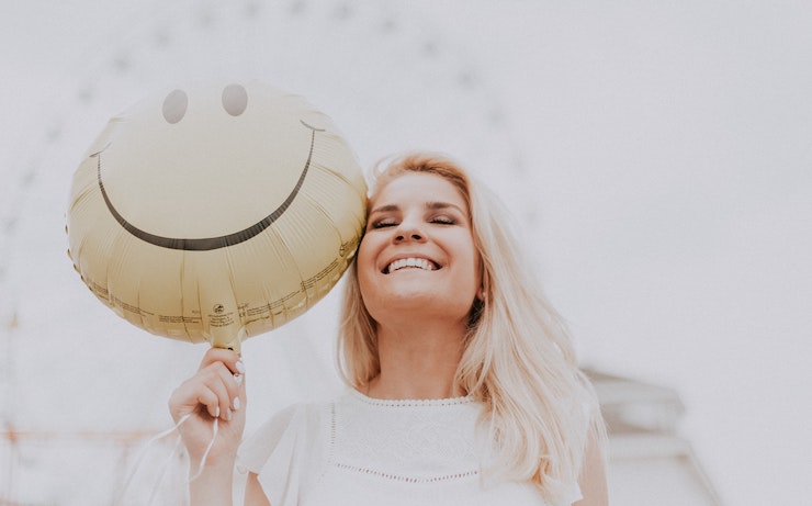 Girl smiling next to smily face balloon