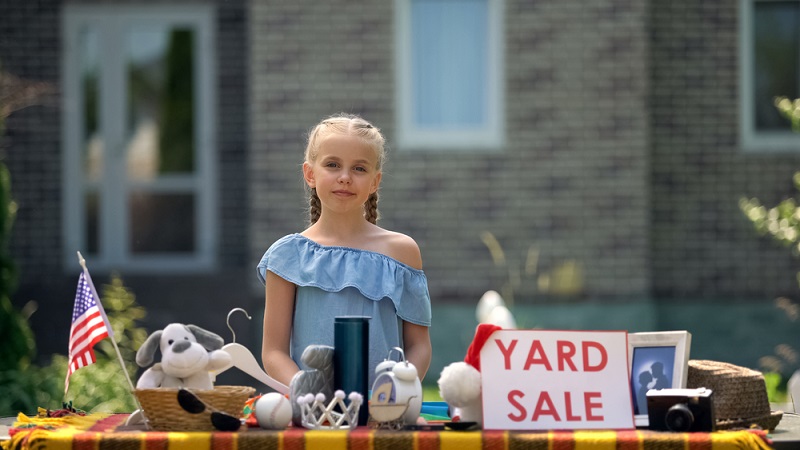 Young business lady selling old toys on yard sale, earning extra pocket money