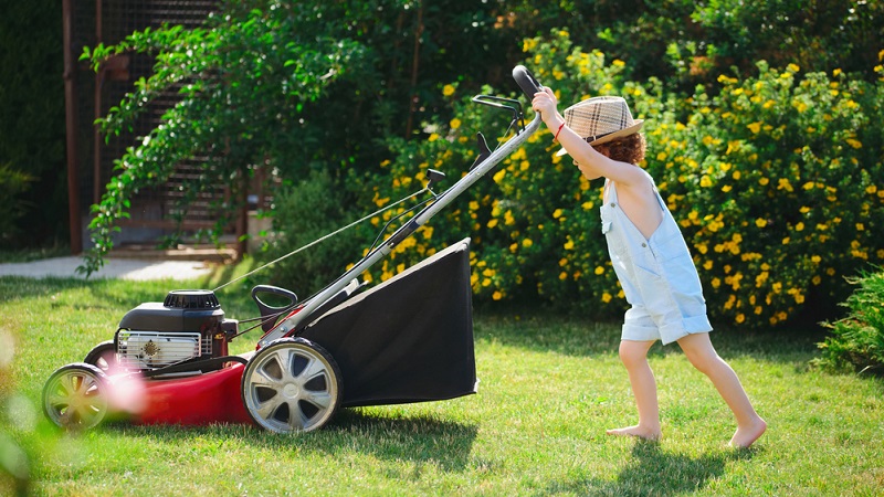kid mows lawn with mower