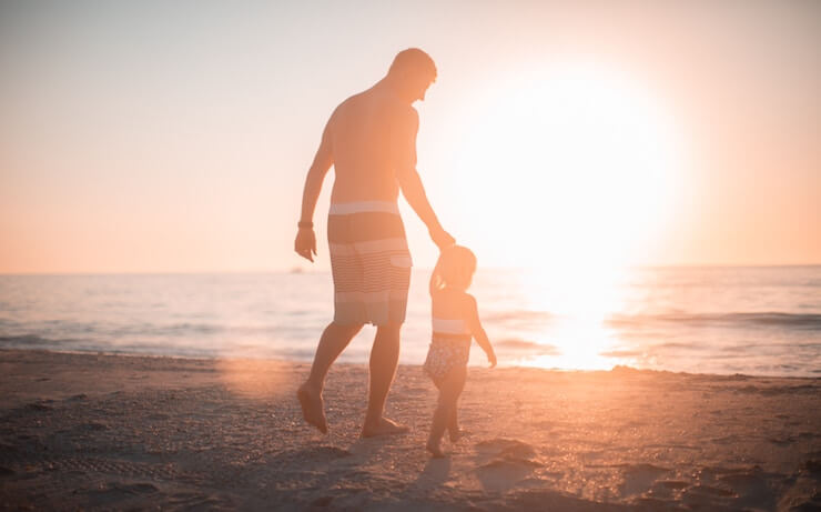 Man holding his daughter's hand at the beach