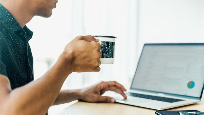 Man looking at stats on his computer while actively drinking coffee