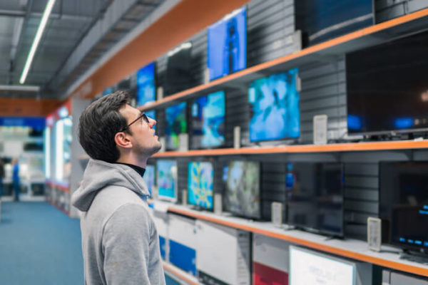Man overwhelmed looking at a wall of TVs for sale