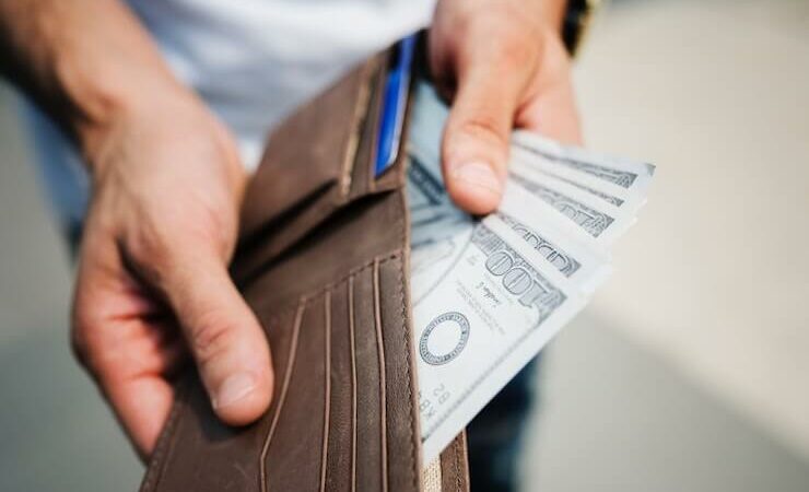 Man taking hundreds of dollars out of his leather wallet