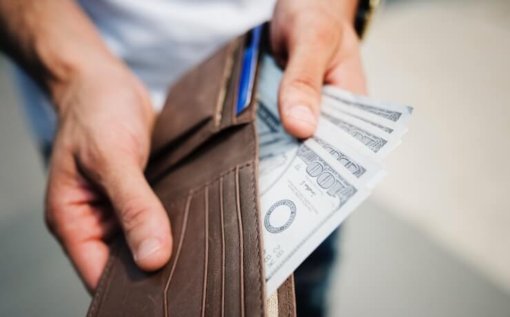 Man taking hundreds of dollars out of his leather wallet