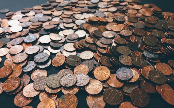 A bunch of pennies and coins spread across a table