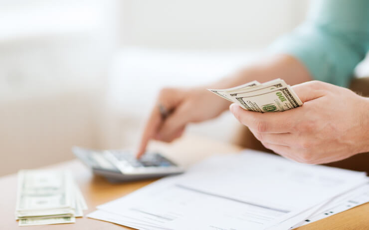 Person counting their cash using a calculator to figure out how much to put into their 401k