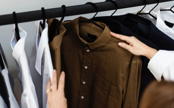 Person going through a rack of shirts with collars and black hangers
