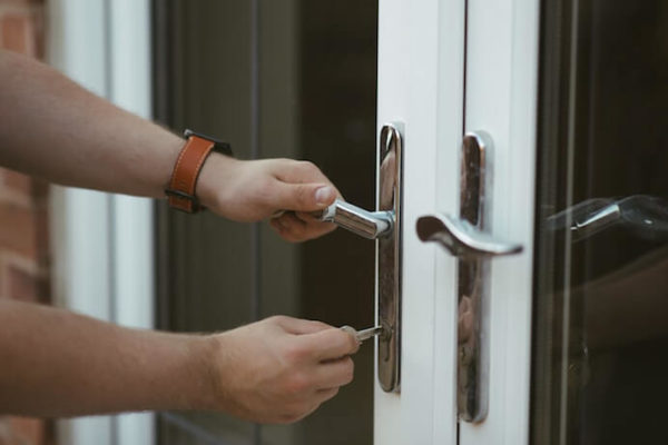 person wearing leather watch unlocking door with glass windows