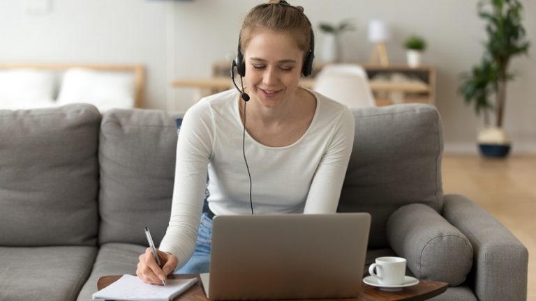 Focused teen wearing headset working online with a laptop