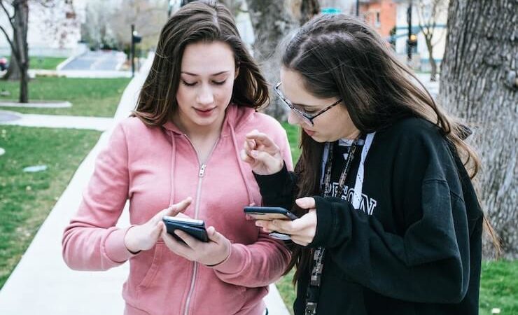 Two teenage girls sending each other money through their phones using an app