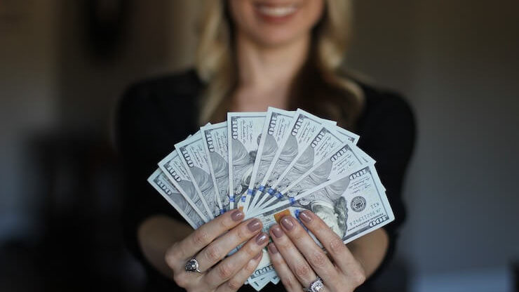 Business woman holding a fan of cash while smiling
