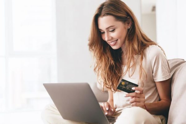woman looking at computer with credit card in hand