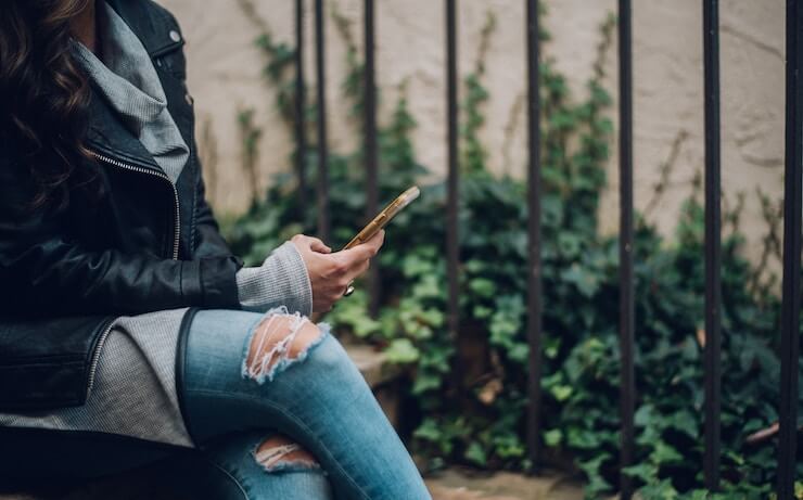 Woman looking at debt payoff apps on her phone sitting outside