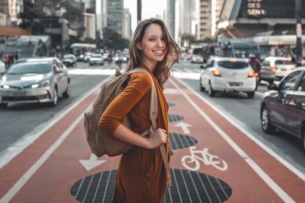 Woman excited about traveling in a city holding a backpack